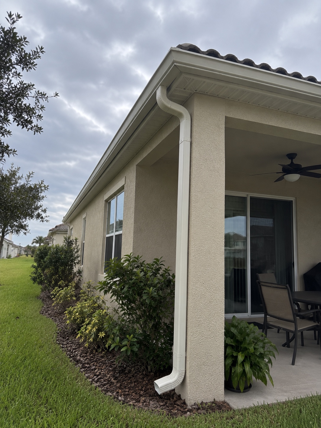 Patio roofline with white gutters and a downspout